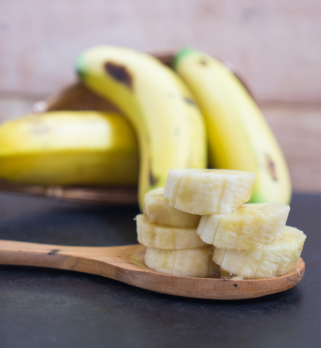 Banana slides in a wooden ladle on blurred banana background,